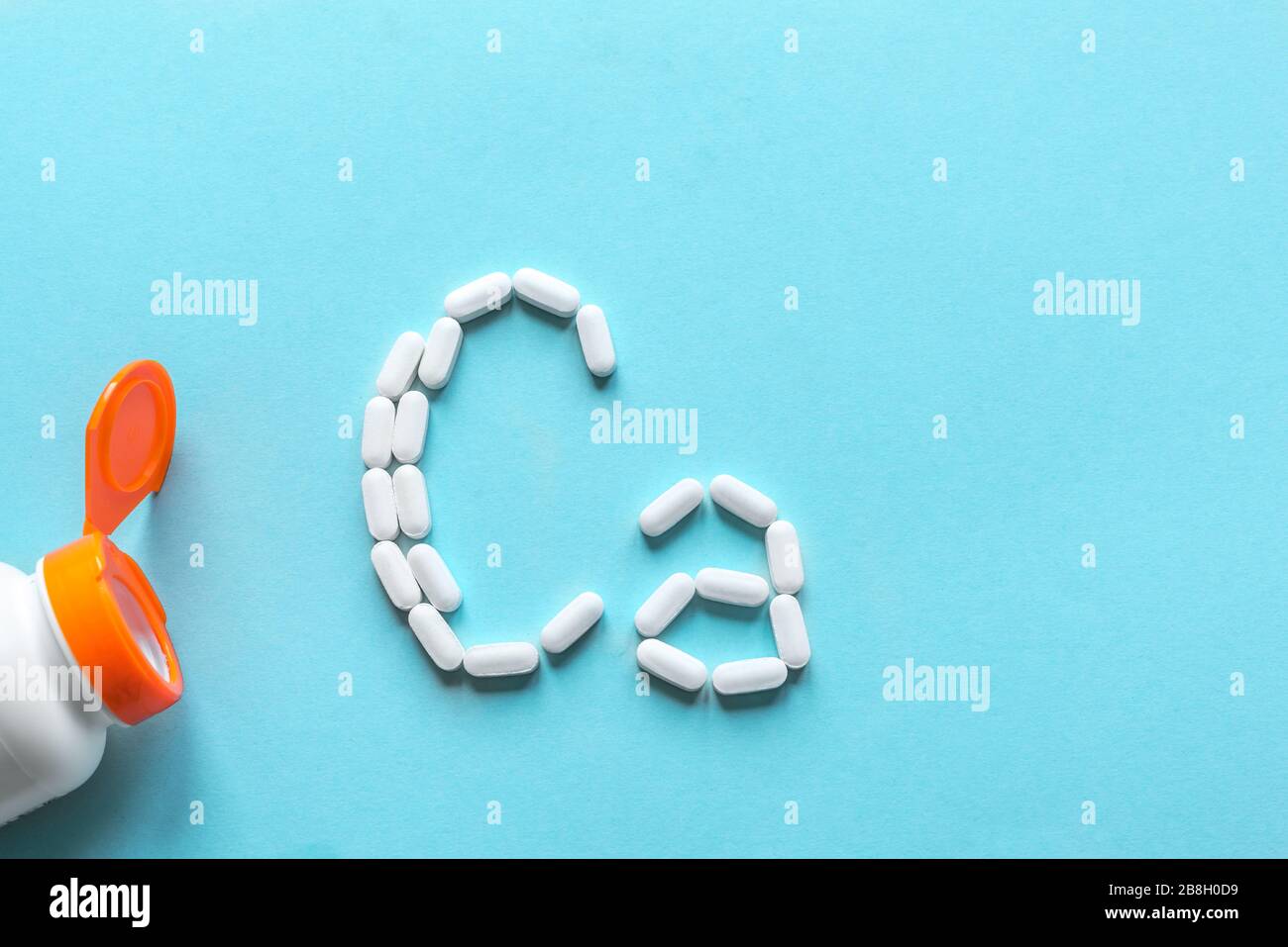 Kalziumtabletten. Weiße Pillen, die Form eines Ca-Alphabets auf blauem Hintergrund bilden, Kopierbereich, Draufsicht. Stockfoto