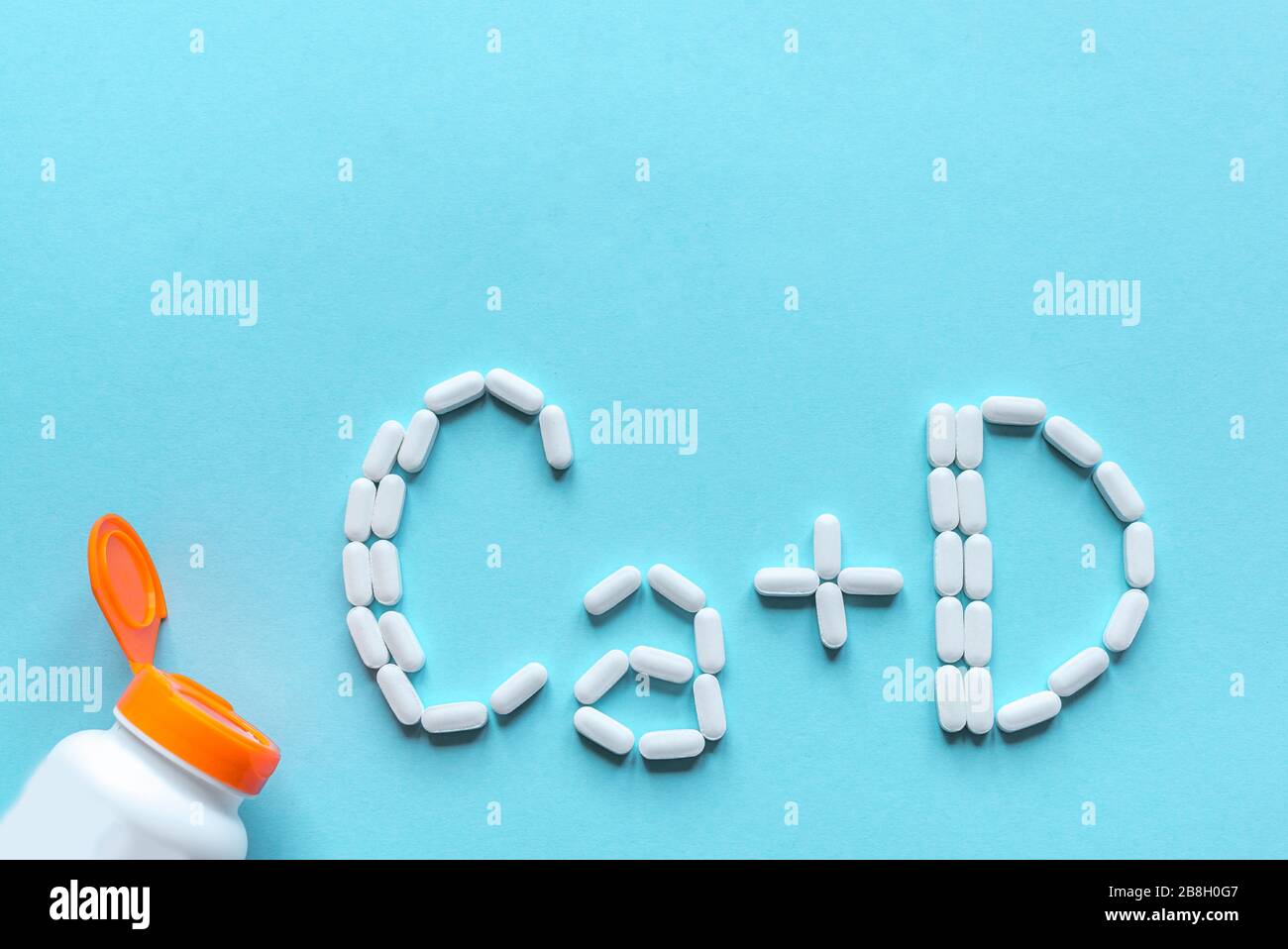 Kalzium und Vitamin D Generische Tabletten. Weiße Pillen, die Form eines Ca+D-Alphabets auf blauem Hintergrund bilden, Kopierbereich, Draufsicht. Stockfoto