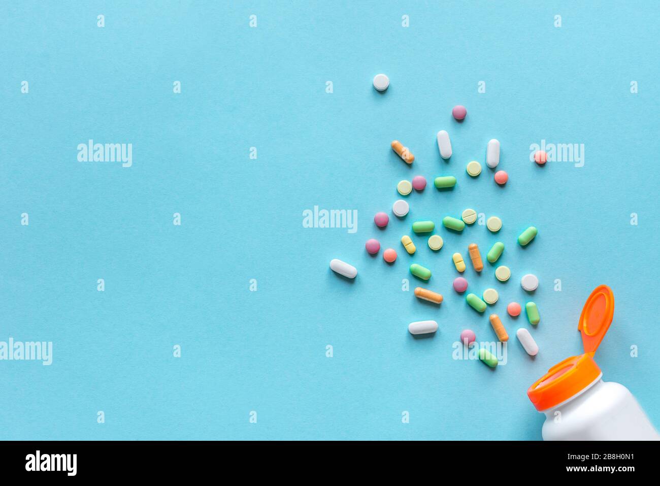 Flasche mit verschiedenen bunten Pillen, Tabletten auf blauem Hintergrund, Draufsicht, Kopierraum. Vitamine und Generika, Pharmazie und Medizin Konzept. Stockfoto