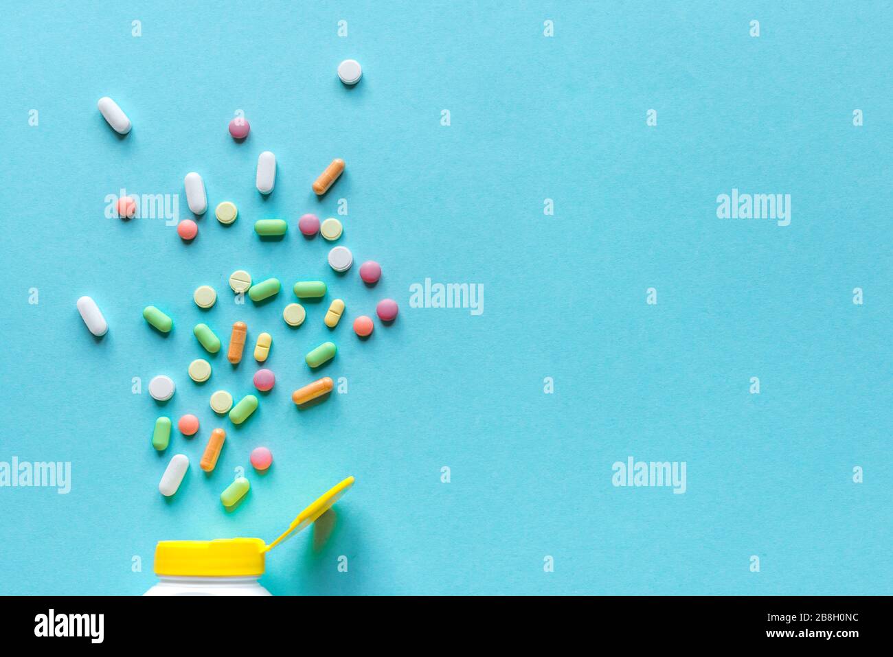 Flasche mit verschiedenen bunten Pillen, Tabletten auf blauem Hintergrund, Draufsicht, Kopierraum. Vitamine und Generika, Pharmazie und Medizin Konzept. Stockfoto