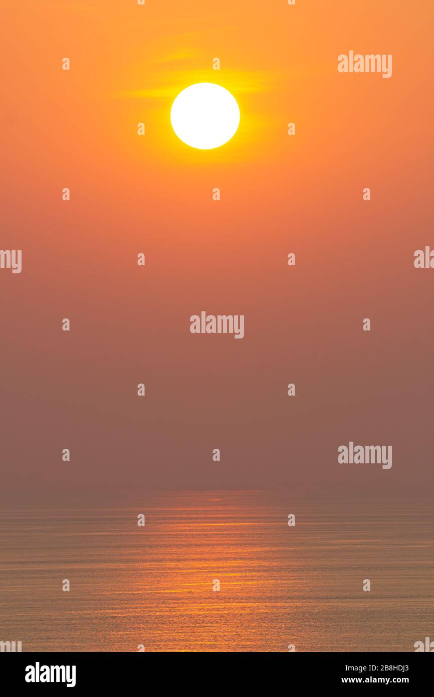 Sonnenuntergang, die Meeresoberfläche, die die Sonne in Orange reflektiert. Klarer Himmel, wolkenlos orange Stockfoto