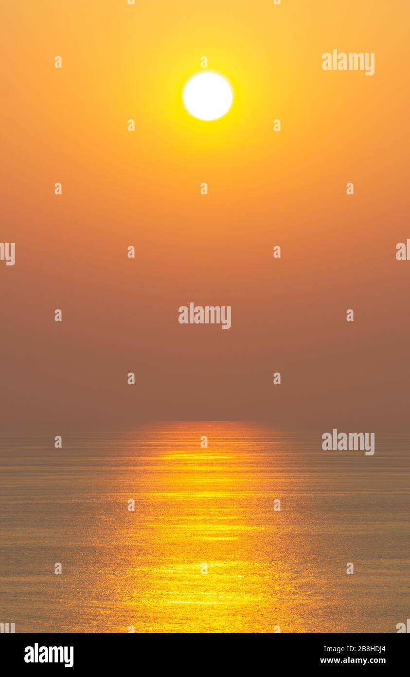 Der Sonnenuntergang, die Meeresoberfläche reflektiert das Sonnenlicht in Gold. Klarer Himmel, Orange ohne Wolken Stockfoto
