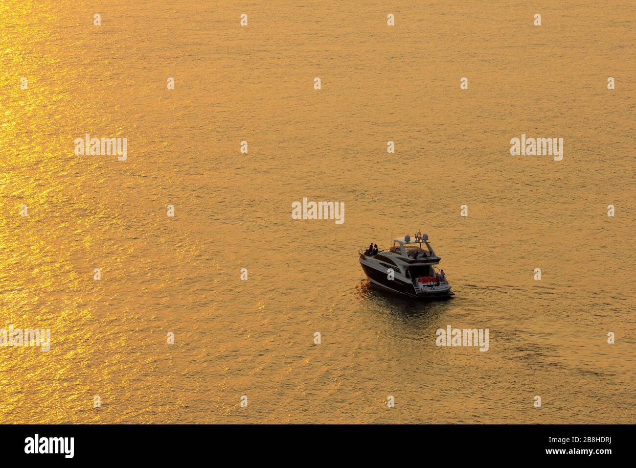 Der Sonnenuntergang an der Meeresoberfläche spiegelt die Sonne in Gold wider: Der Touristenpark das Boot, um die Schönheit der Sonne zu sehen. Stockfoto