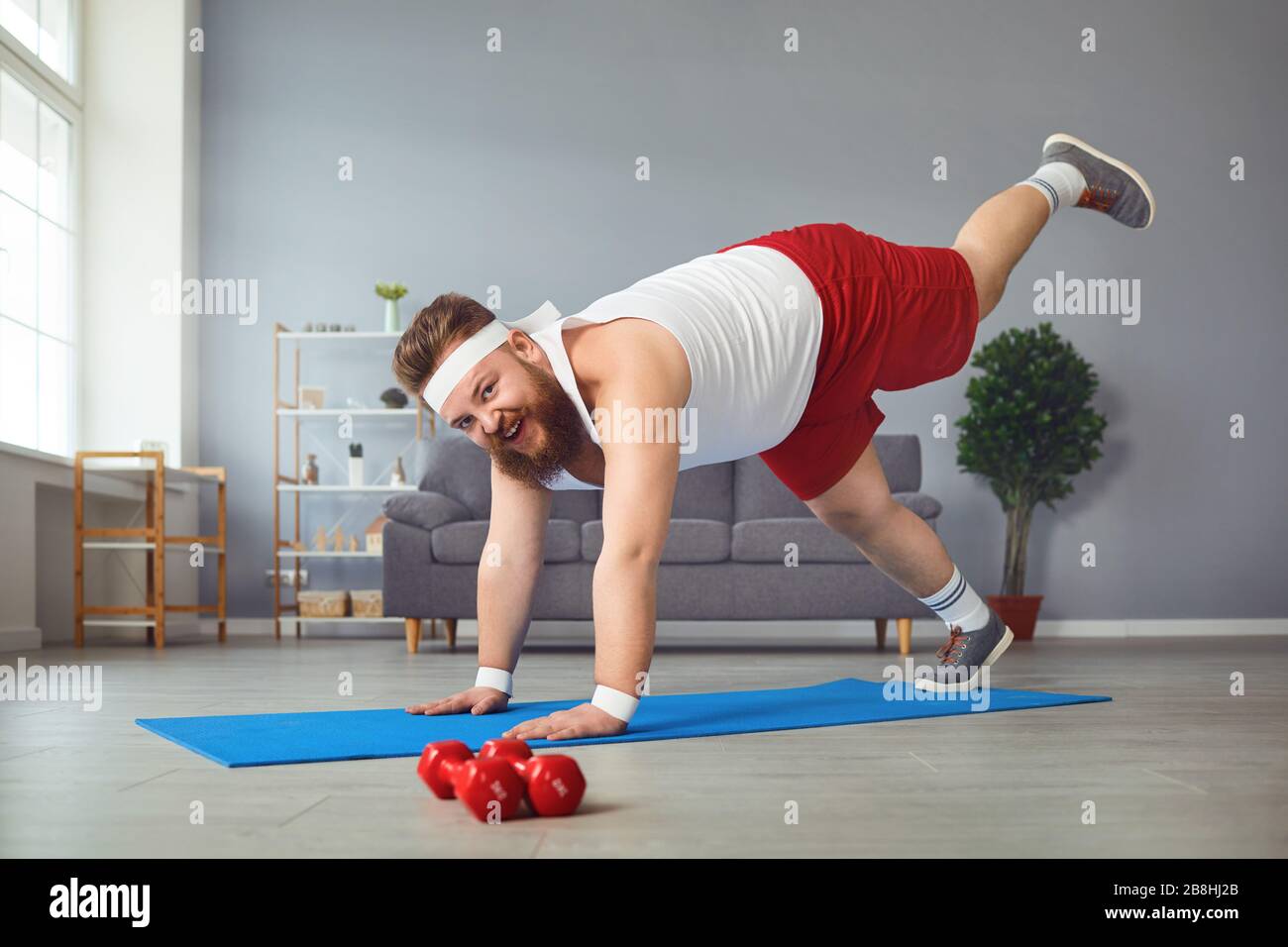 Lustiger fetter Mann, der Yoga-Übungen im Raum macht. Stockfoto