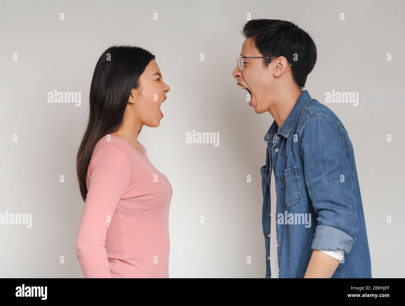 Asiatischer Mann und Frau schreien über grauem Hintergrund Stockfoto