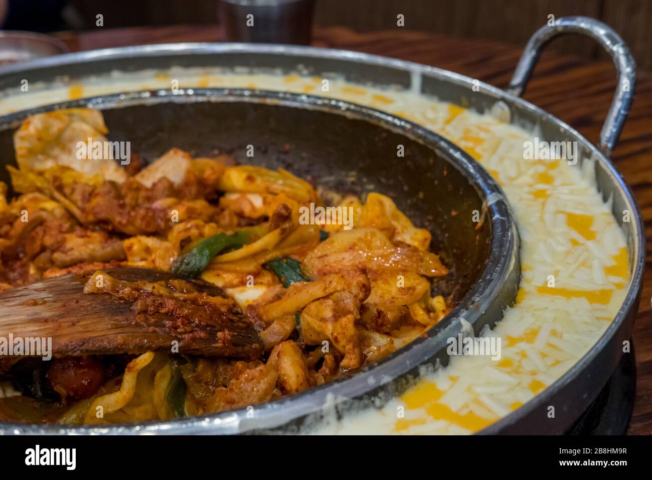 DAK Galbi, Koreanisch würzig rühren gebratenes Huhn mit pflanzlicher und koreanischer würziger Sauce oder Gochujang in großer heißer Pfanne mit Käse Stockfoto