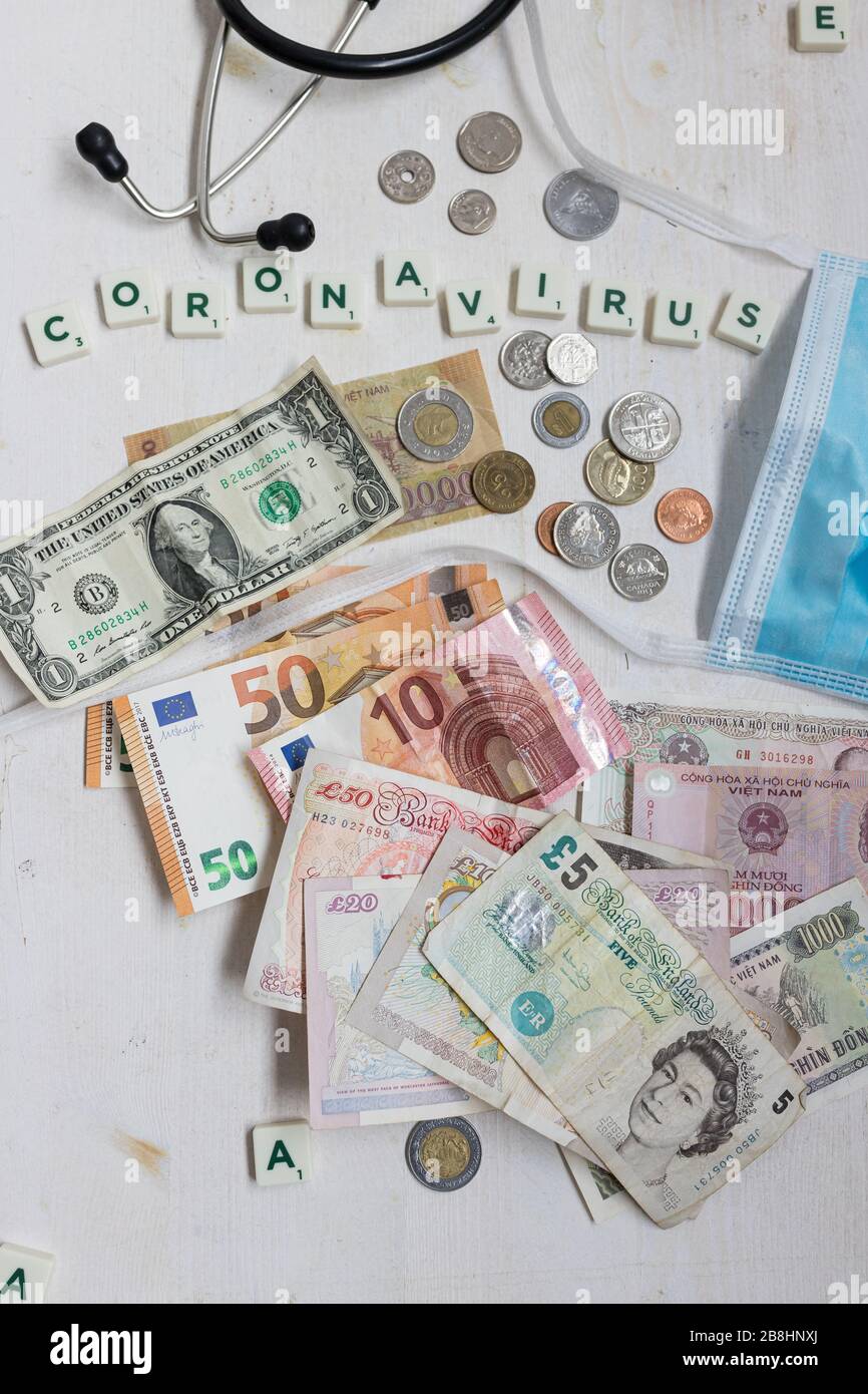 Overhead-Ansicht von Euro, Dollar, Pfund und mehr. In der Oberseite das Wort Coronavirus. Stockfoto