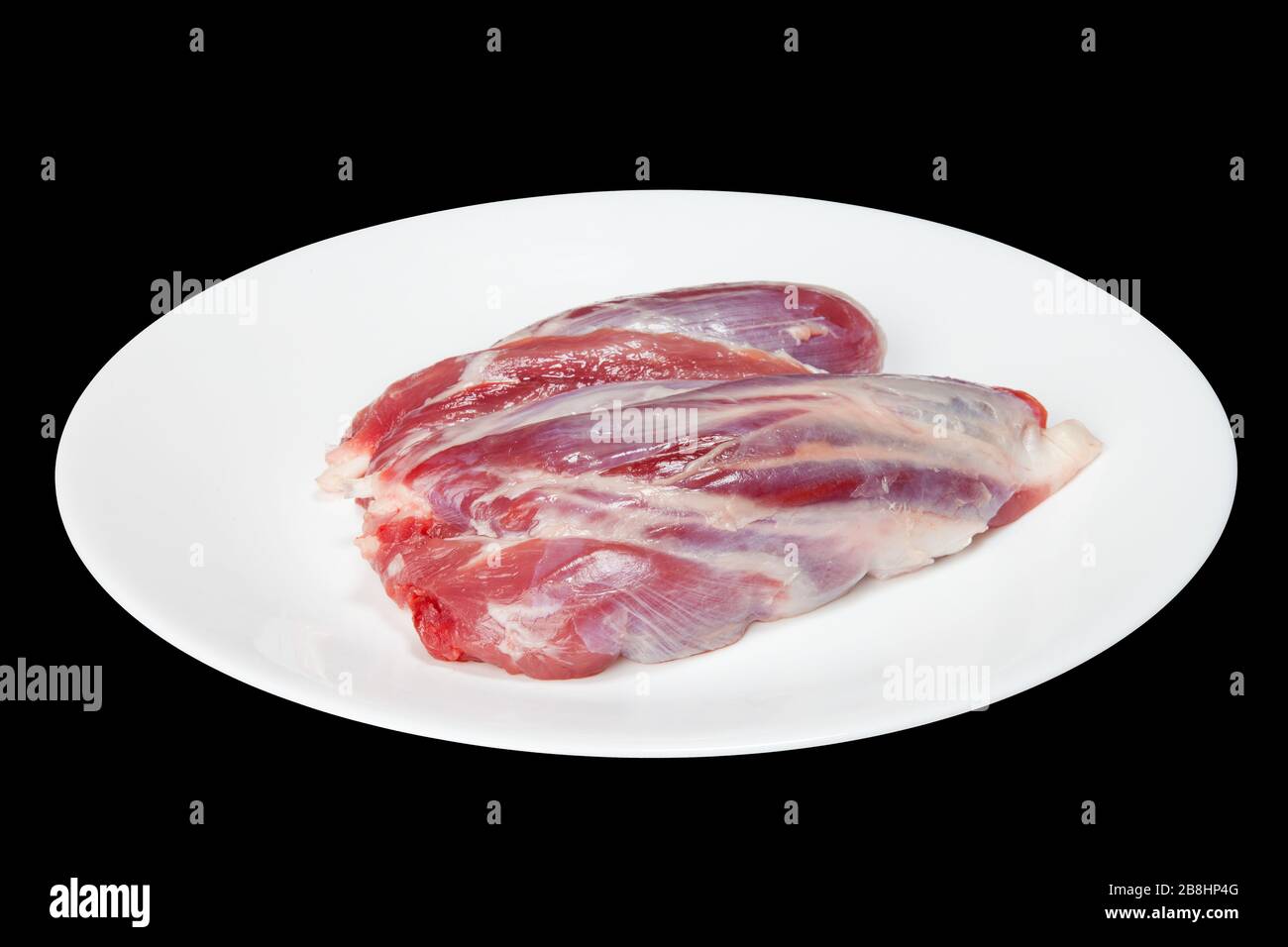 Stücke rohes Fleisch auf einer weißen Platte sind auf schwarzem Grund isoliert Stockfoto