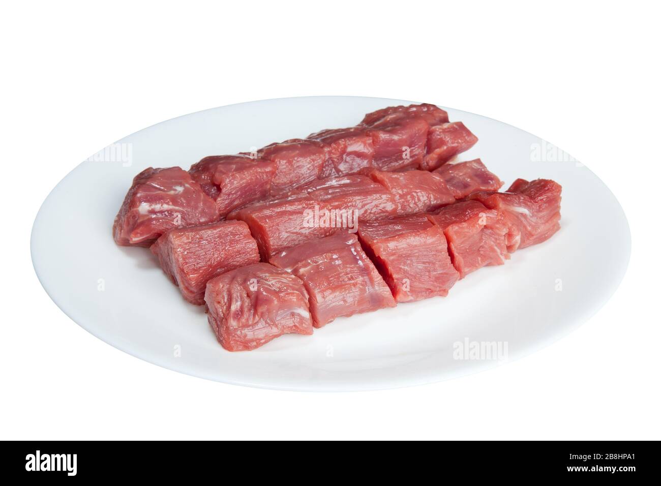 Stücke rohes Fleisch auf einer weißen Platte sind auf weißem Grund isoliert Stockfoto