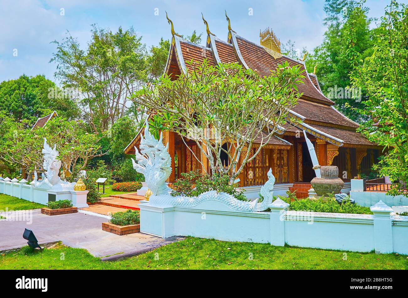 Das Gelände des üppigen Laos-Gartens mit Nachbildung des Holztempels Wat Xieng Thong, bewacht von weißen Naga-Schlange, Rajapruek-Park, Chiang Mai, Thailand Stockfoto