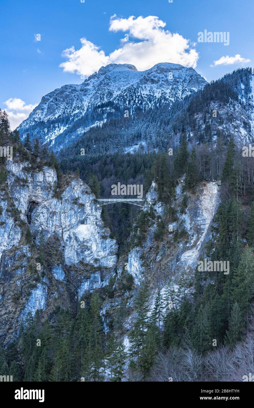 Atemberaubender Blick auf die Marienbrücke (Marienbrücke) über die Pollat (Poellat) Gerge in der Nähe des berühmten Schlosses Neuschwanstein im Winter mit Schneebergen Stockfoto