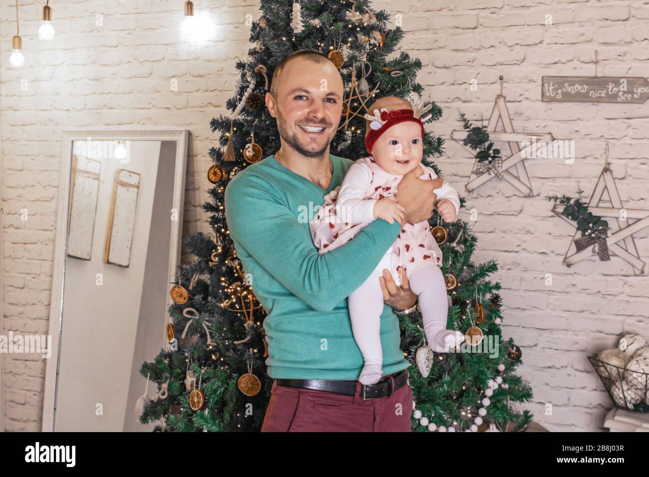 Fröhlicher junger Vater mit seinem süßen Baby auf dem weihnachtsfoto Stockfoto