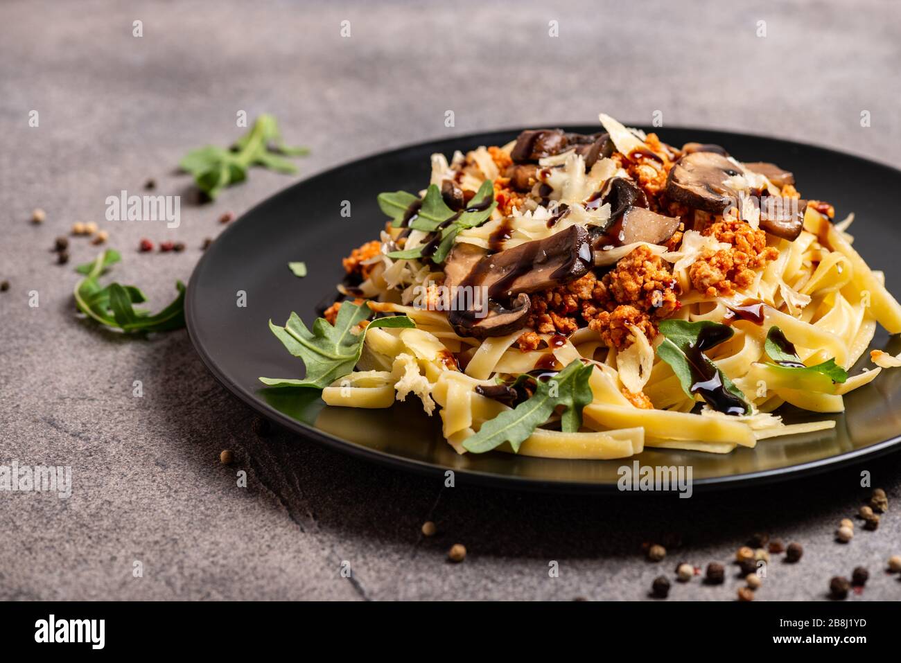 Bolognese Pasta mit Champignons und Arugula zubereitete Balsamiksoße. Nahaufnahme. Stockfoto