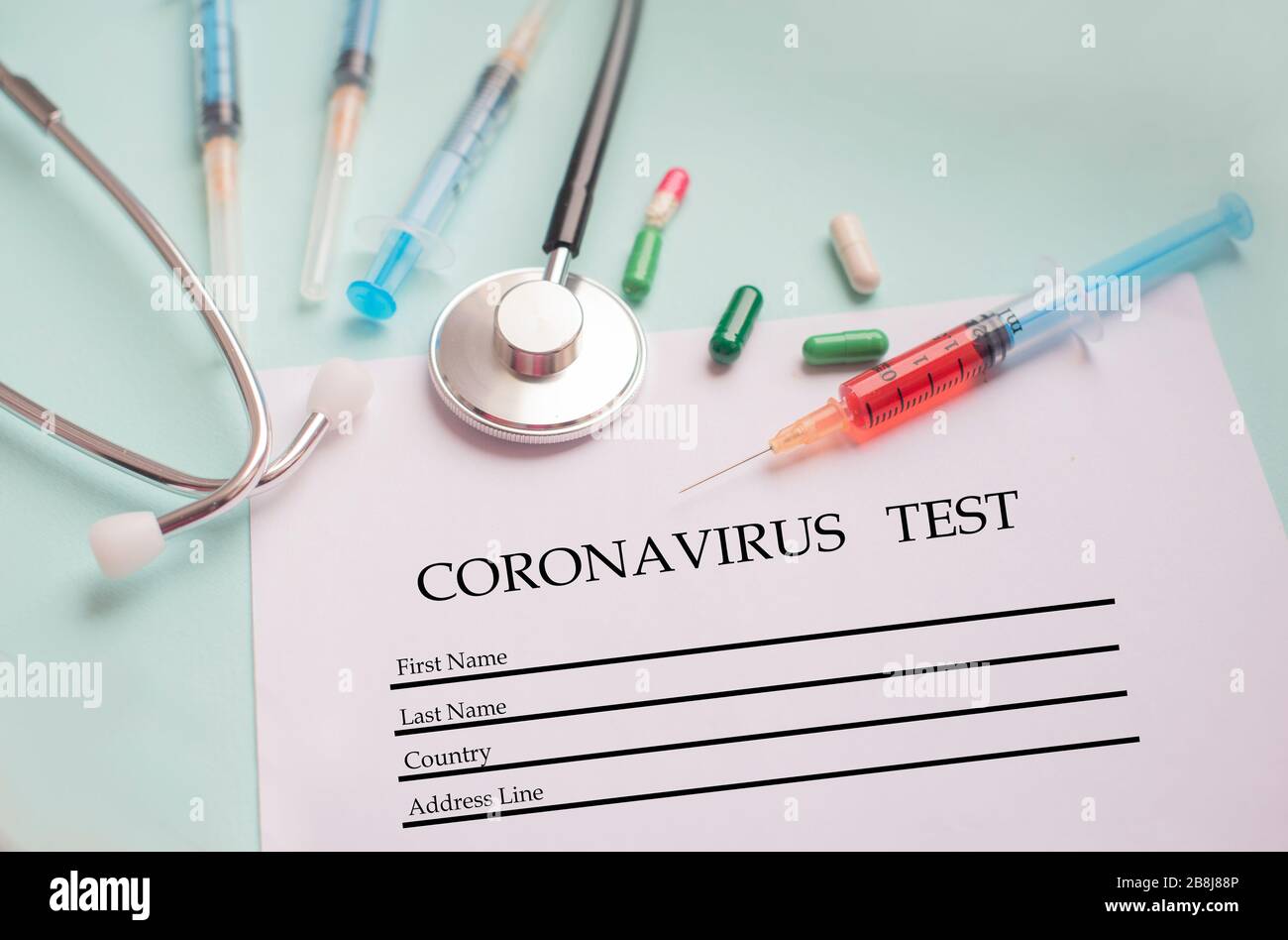 Eine Spritze mit einem Bluttest und ein Stethophonendoskop mit Ein Patientenfragebogen und Tabletten für eine Pandemie eines Cornovirus Stockfoto