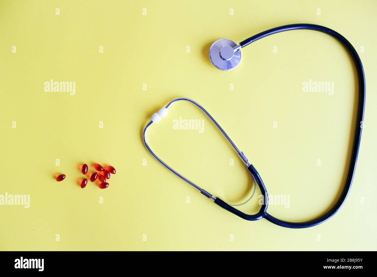 Medizinisches Stethoskop, Stethoskop und rote Pillen auf gelbem Hintergrund. Pillen und Behandlungen. Stockfoto