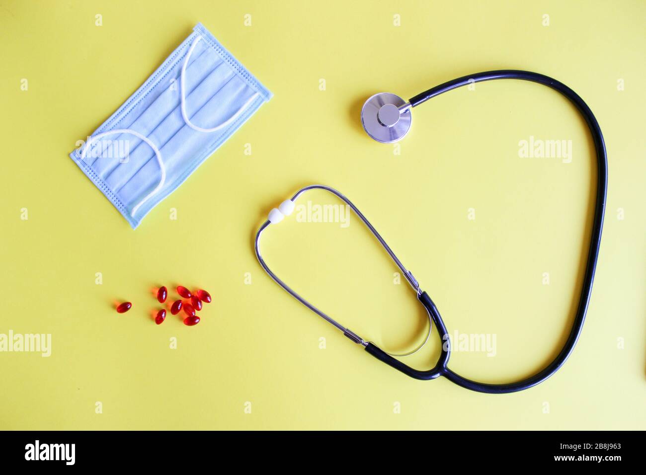 Medizinisches Stethoskop, Stethoskop und rote Pillen auf gelbem Hintergrund. Pillen und Behandlungen. Stockfoto