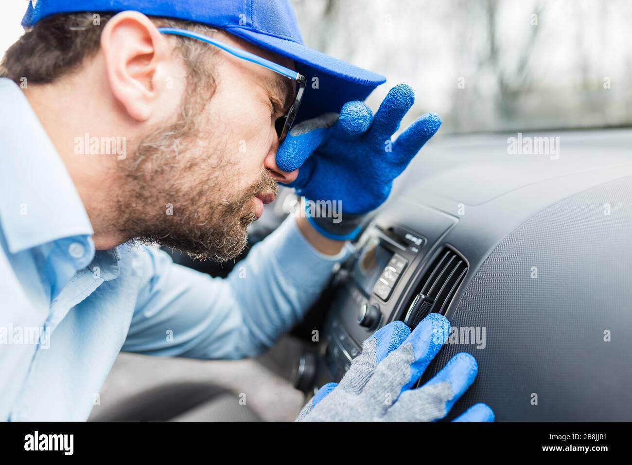 Arbeiter schützten seine Nase vor schlechter Gerüche der Autoklimaanlage. Stockfoto