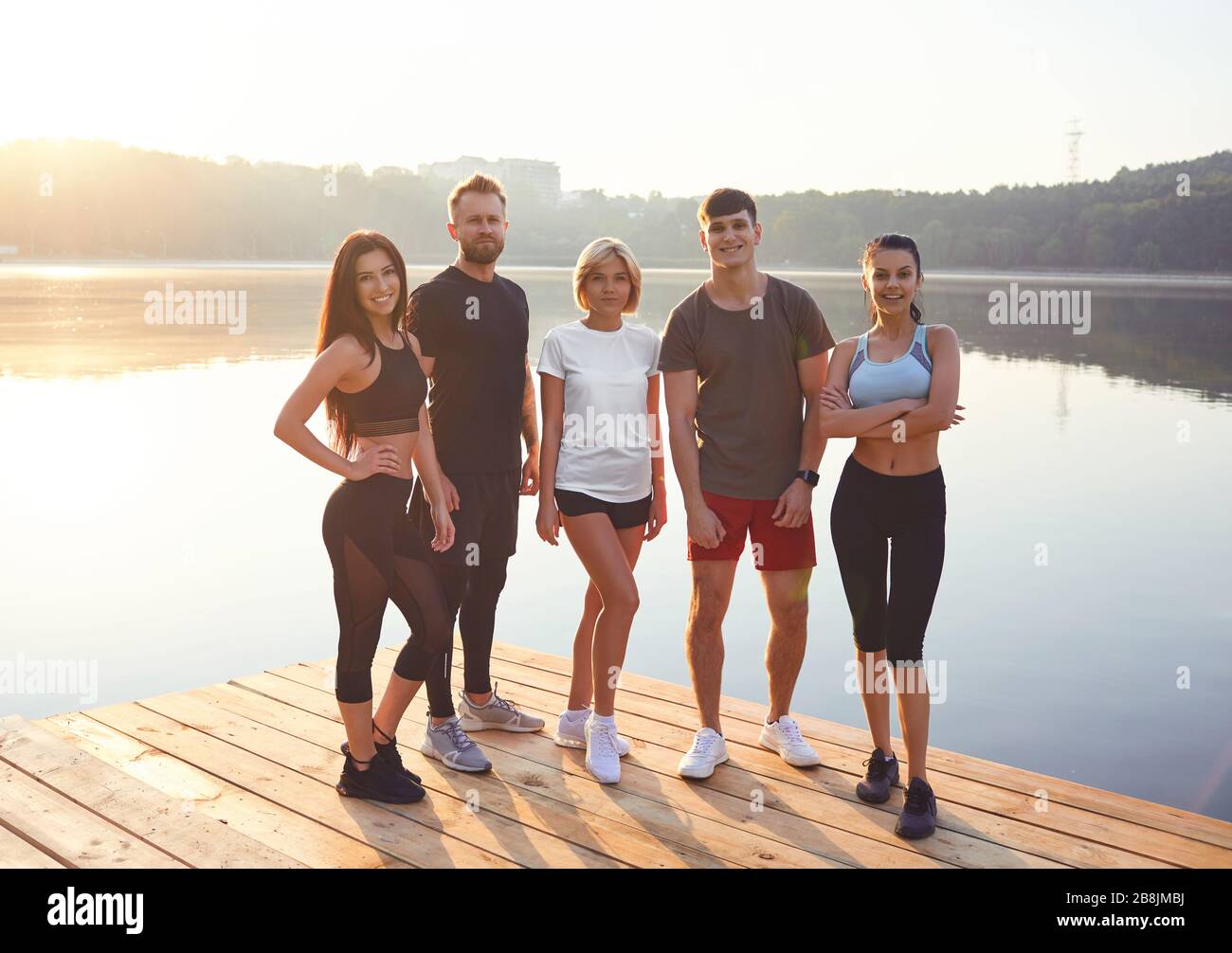 Eine Gruppe von Athleten steht auf dem Hintergrund eines Sees in einem Stadtpark. Stockfoto