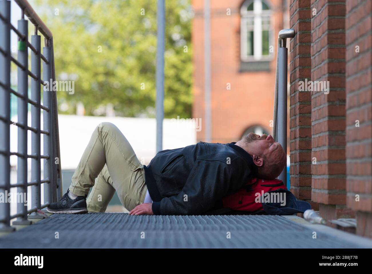 HAMBURG, DEUTSCHLAND - 12. MAI 2018: Betrunkener Mann schläft während der jährlichen Hamburger Hafenjubiläumstage auf der Straße Stockfoto