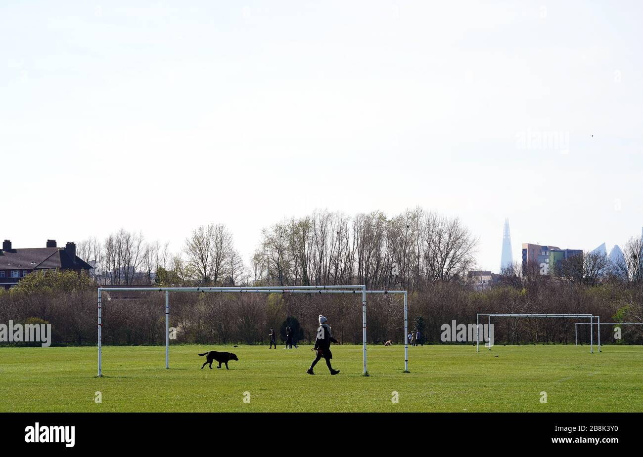 Hundegänger bei Hackney Marshes in London, da der gesamte Breitenfußball in England auf absehbare Zeit verschoben bleibt. Stockfoto