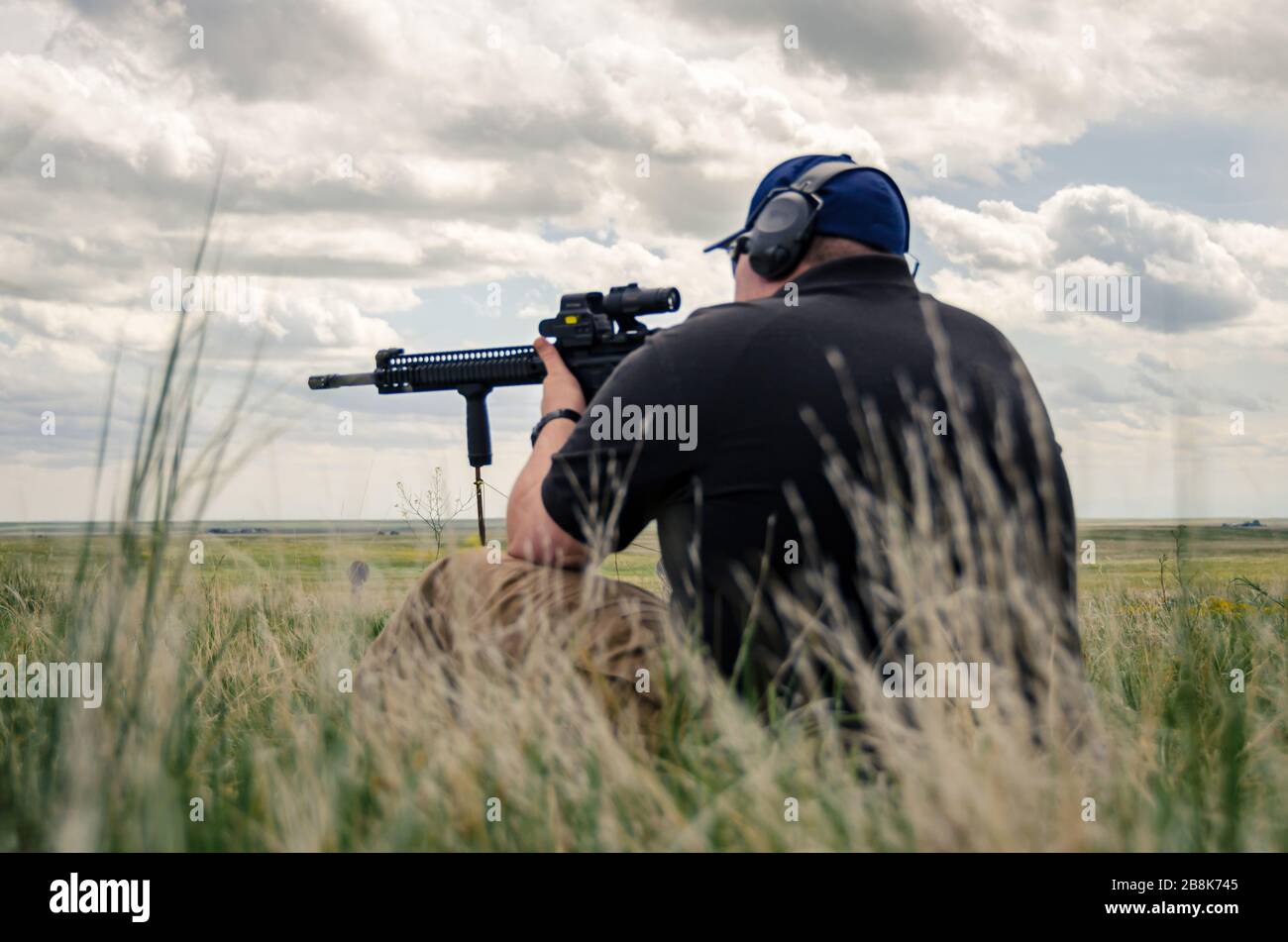 Mann sitzt und feuert automatisches Gewehr.Waffen Training und Live-Beschuss auf offener Waffenpalette, amerikanische Kultur Fort Collins USA Stockfoto
