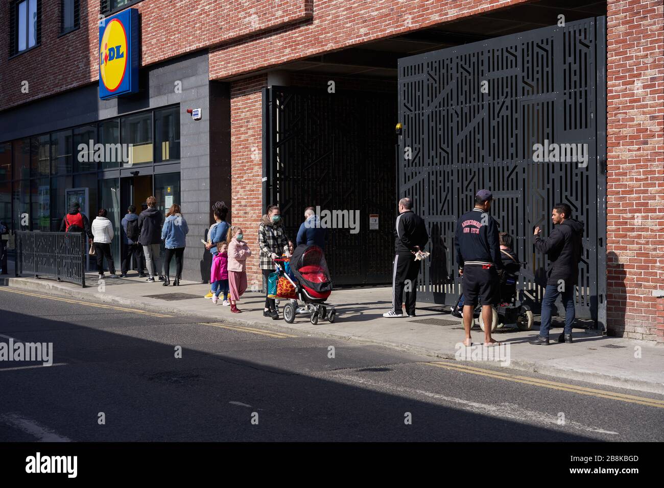 Menschen, die während der Pandemie von Coronavirus, Dublin City, irland, vor einem Supermarkt Schlange stehen und dabei eine sichere Entfernung halten. Stockfoto