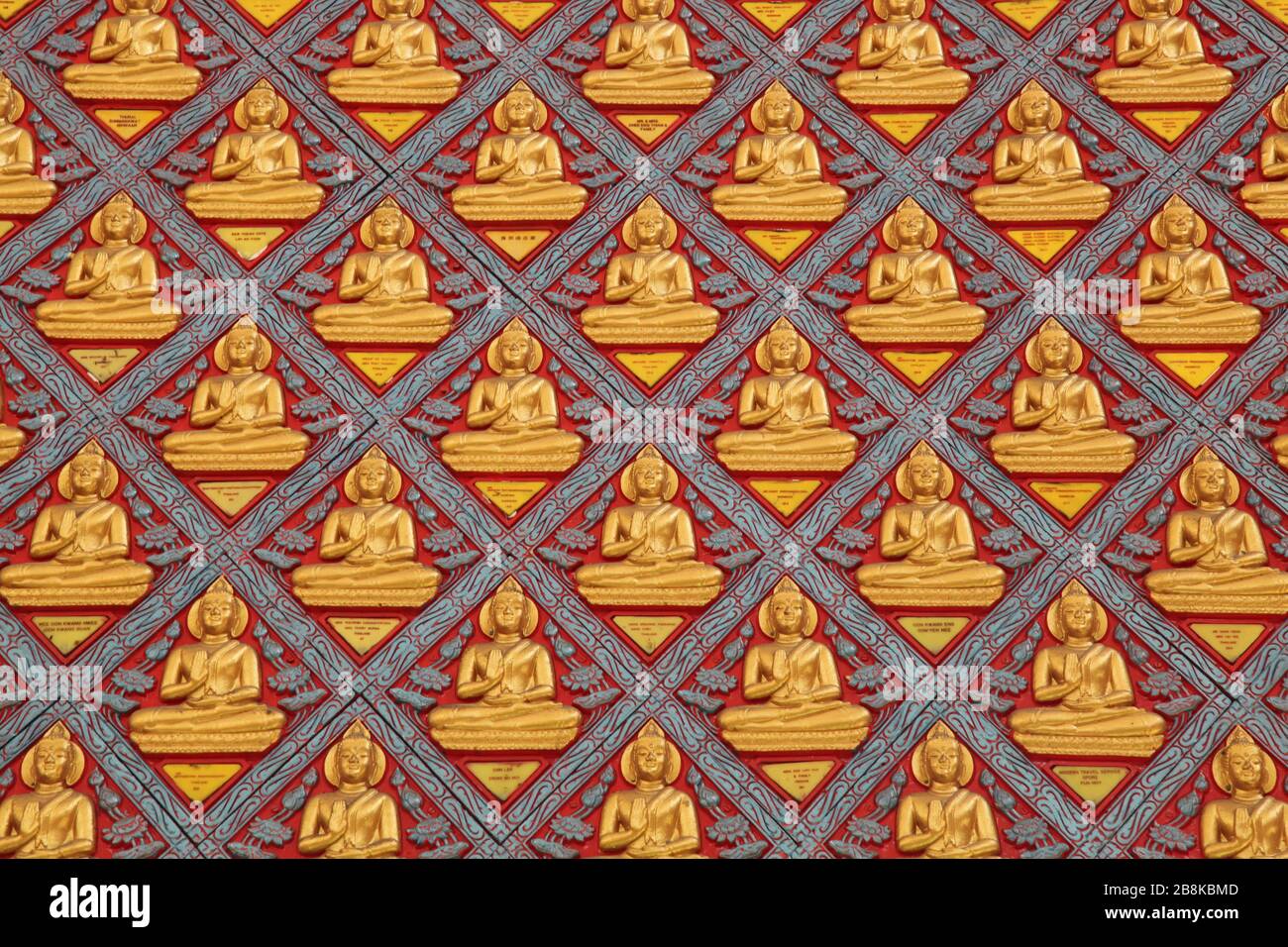 Symmetrisches Wandmuster mit goldenen Buddhas, das als Hintergrund aus dem Wat Chaiya Mangkalaram Tempel in Penang, Malaysia verwendet werden kann Stockfoto