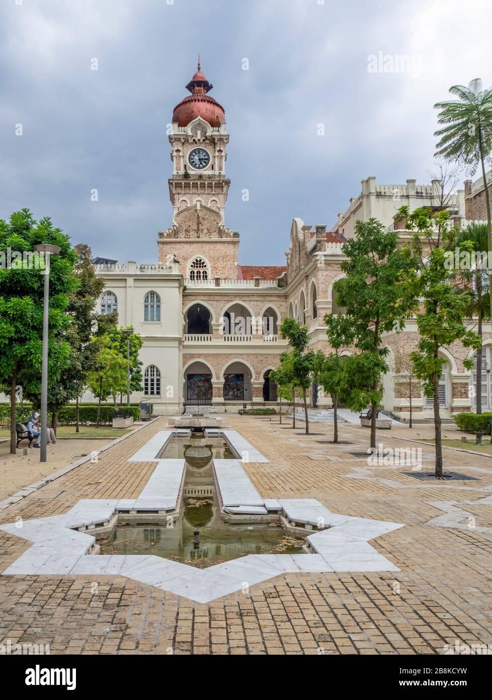 Zentraler Uhrturm mit kupferfarbener Zwiebelkuppel und Teich in Form des islamischen Symbolsterns Rub el Hizb im Sultan Abdul Samad Building Kuala Lumpur Malaysia. Stockfoto