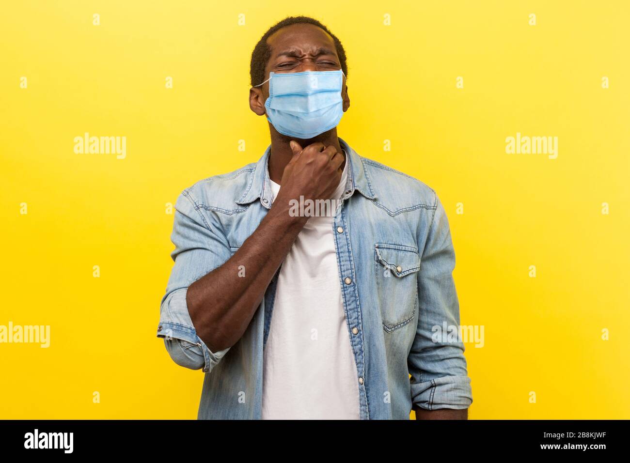 Porträt des aufgebrachten Mannes mit medizinischer Maske, die sein Nackengefühl unwohl hält, an Halsschmerzen, Entzündungen und Grippesymptomen leidet, medizinisches Konzept Stockfoto