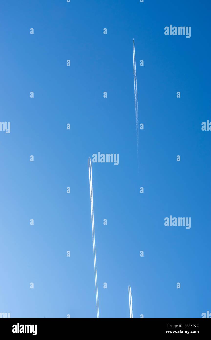 Blick in den hellblauen und wolkenlosen Himmel mit 3 Flugzeugen mit parallel fliegenden und in die gleiche Richtung versetzten Kondensstreifen Stockfoto