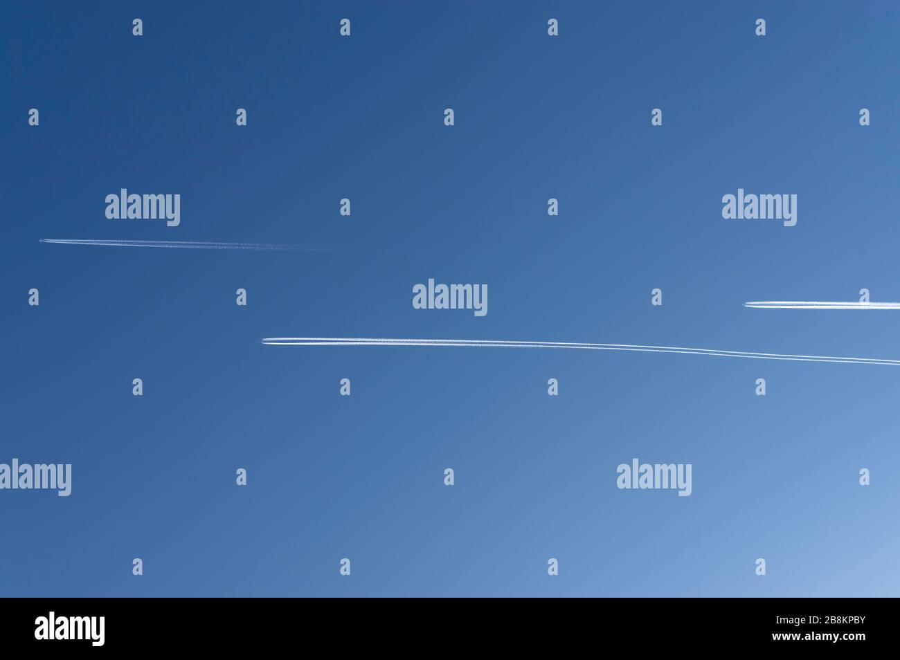 Blick in den hellblauen und wolkenlosen Himmel mit 3 Flugzeugen mit parallel fliegenden und in die gleiche Richtung versetzten Kondensstreifen Stockfoto