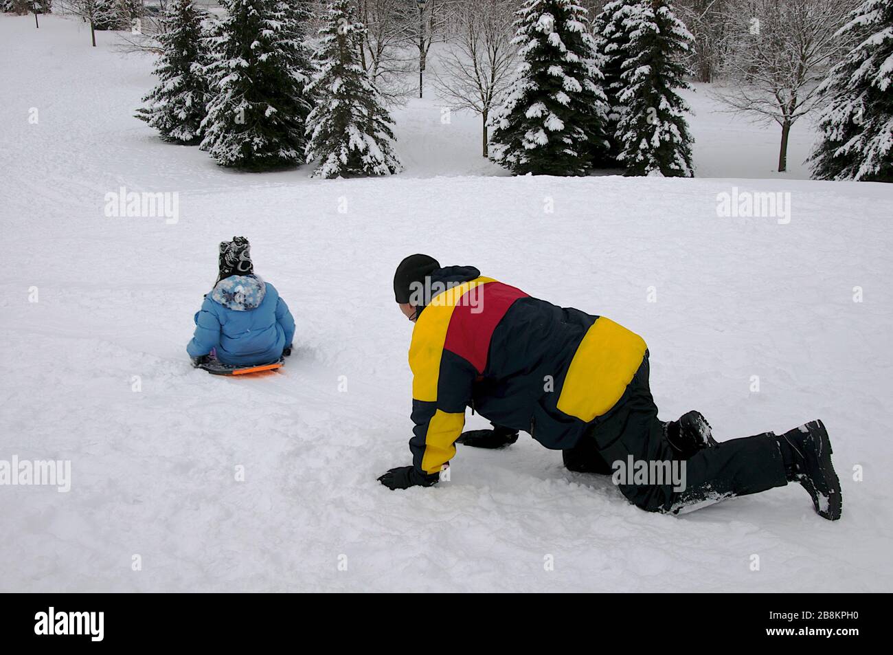 Wintersport-Rodeln - reifer Gesundheitsvater und Sohn spielen Rodeln, Winter, draußen, gesunder Lebensstil. Stockfoto