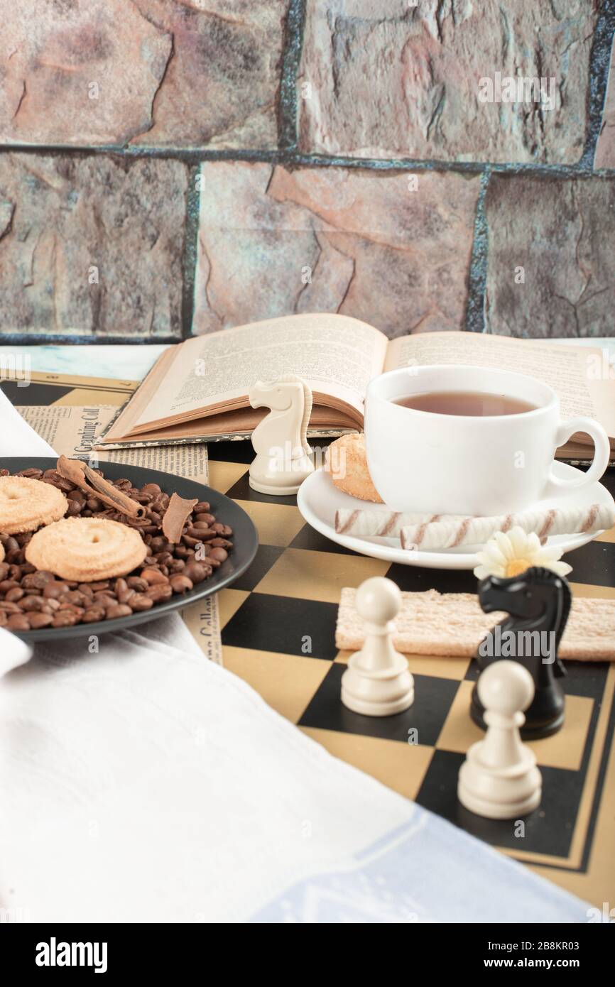 Schachfiguren, eine Tasse Tee, ein Buch und Plätzchen Stockfoto