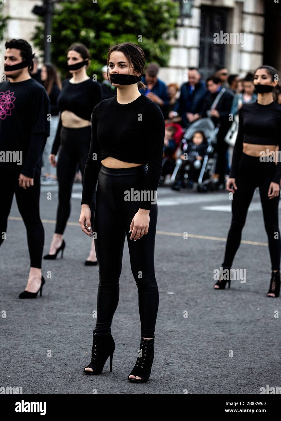 Tanz-Truppe in schwarz gekleidet mit Gesichtsmasken über dem Mund, internationaler Frauentag 2020, Valencia, Spanien. Stockfoto