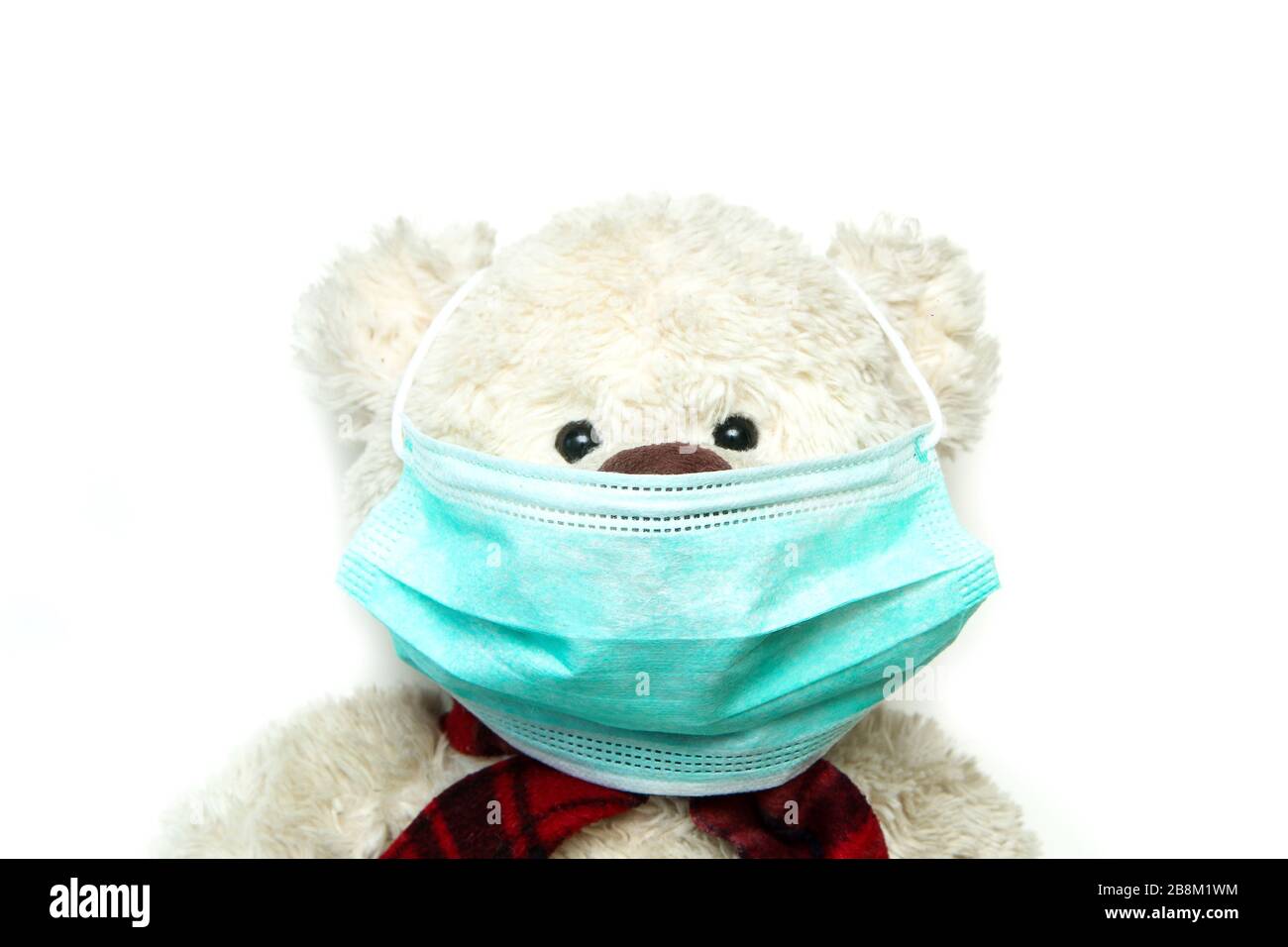 Der Plüschteddy mit einer Maske im Gesicht als Symbol für den Schutz vor Viren wie Corona-Virus. Jeder muss eine Maske tragen. Stockfoto
