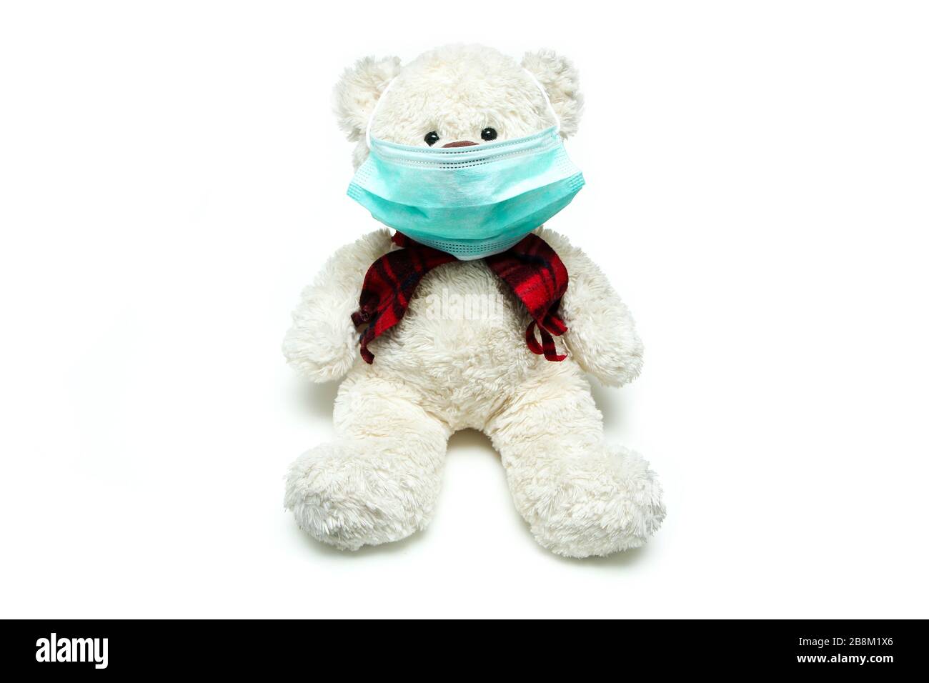Der Plüschteddy mit einer Maske im Gesicht als Symbol für den Schutz vor Viren wie Corona-Virus. Jeder muss eine Maske tragen. Stockfoto