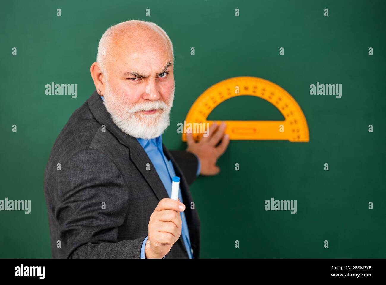 Ernst und streng. Heimlernen. Lehrer für ältere Männer verwenden ein Werkzeug für Fortziehende. Bärtiger Tutor zieht mit einem Lineal auf die Tafel. Zurück zur Schule. Lieblingsfach und -Disziplinen. Ausbildung in der Schule. Stockfoto
