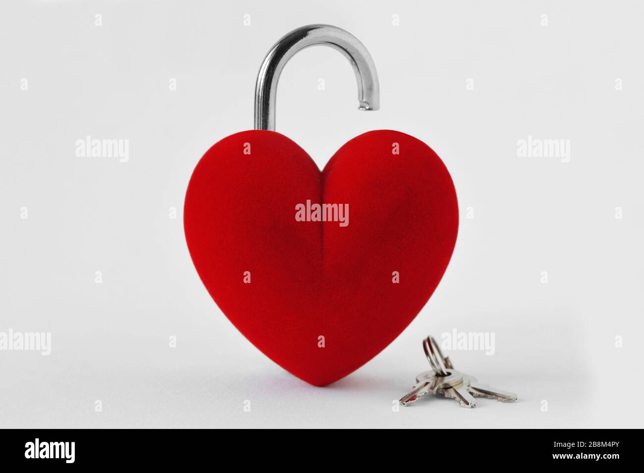 Offenes, herzförmiges Vorhängeschloss mit Schlüsseln auf weißem Hintergrund - Liebeskonzept Stockfoto