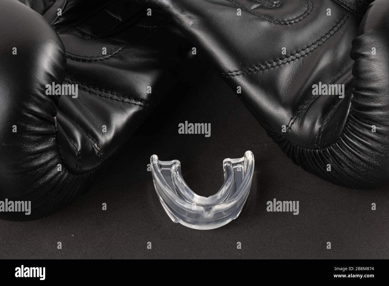 Boxhandschuhe und Mundschutz auf schwarzem Hintergrund, Sportfotografie Stockfoto