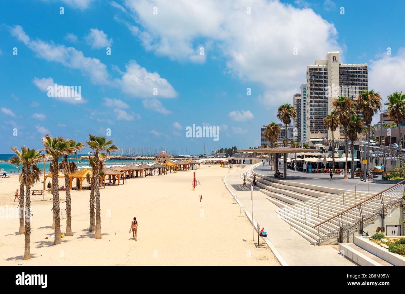 Menschen am öffentlichen Strand entlang der Mittelmeerküste und der Promenade mit modernen Hotels in Tel Aviv, Israel. Stockfoto