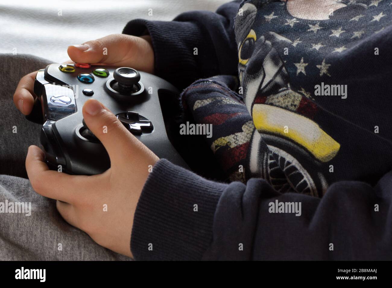 Hände eines sieben Jahre alten Jungen, der mit einem drahtlosen Gamepad mit Xbox One spielt. Home-Entertainment-Technologie. Stockfoto