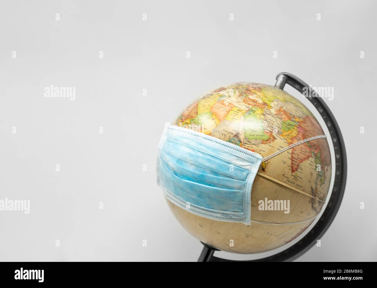 Planet Erde weht eine Operationsmaske, Konzept des Corona-Virus auf weißem Hintergrund Stockfoto