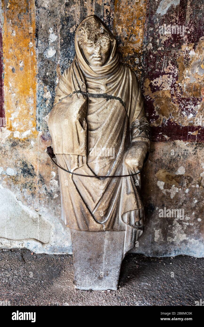 Antike römische Statue, die vor einer Mauer in den Ruinen von Pompeji, Kampanien, Italien steht. Stockfoto