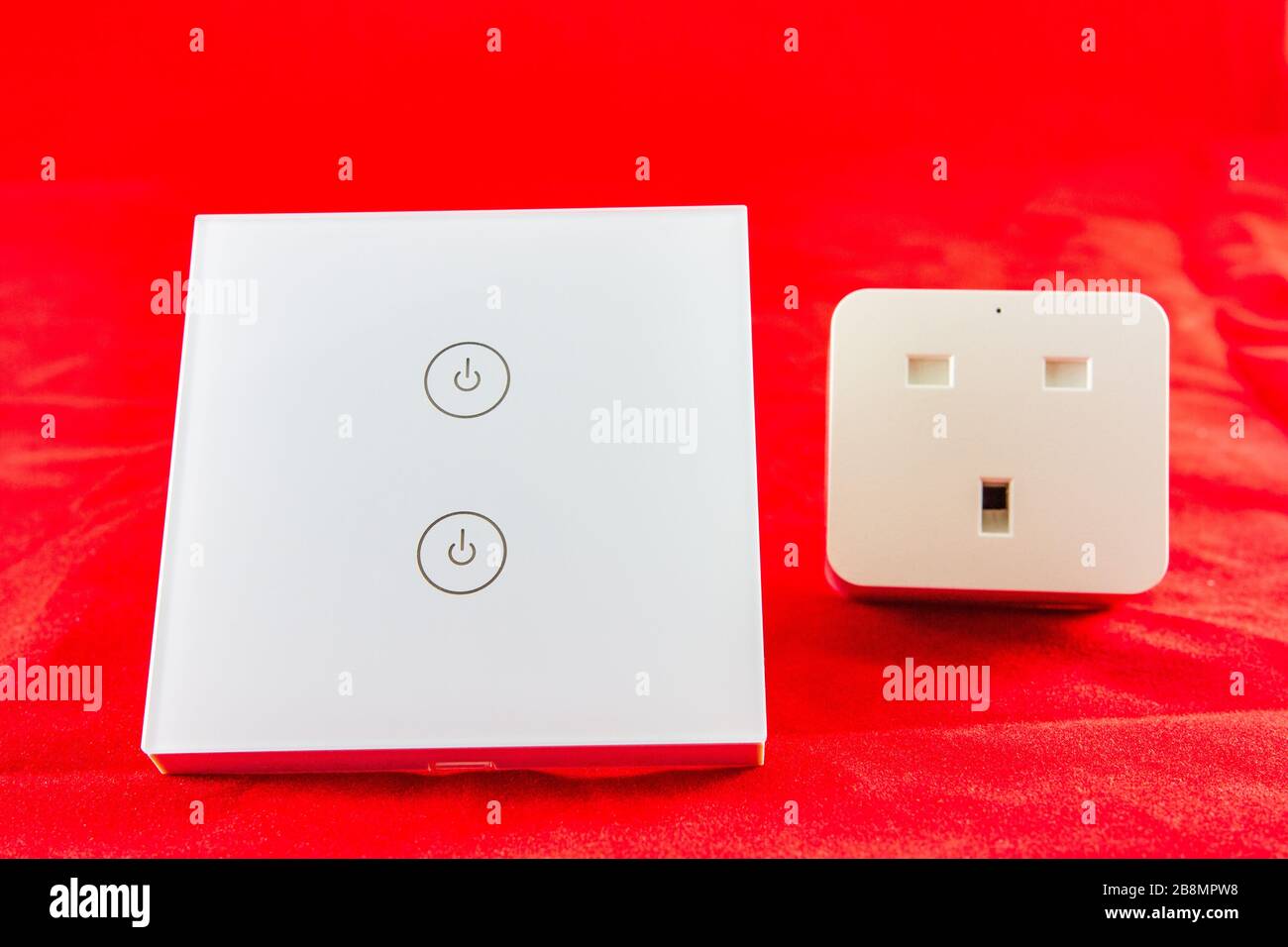Smart Wi-Fi-Switch mit Unterstützung für die Steuerung über Mobiltelefonanwendung. Wird auf rotem Hintergrund aufgenommen Stockfoto