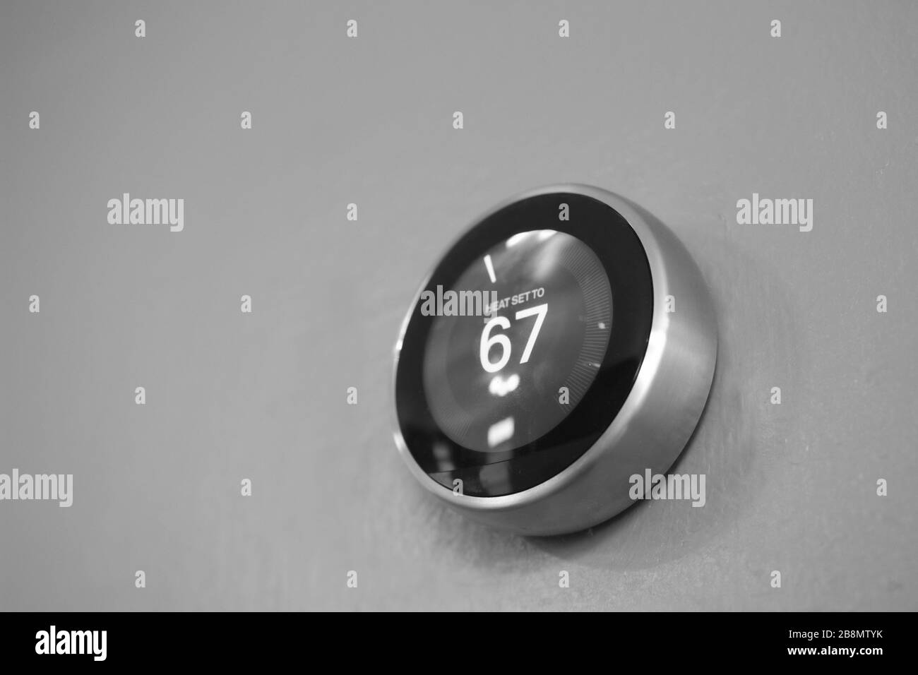 Smart Thermostat an hellblauer Wand von unten isoliert. Mit der intelligenten Heimtechnologie sparen Sie Geld beim Erwärmen und Kühlen. Schwarz und Weiß Stockfoto