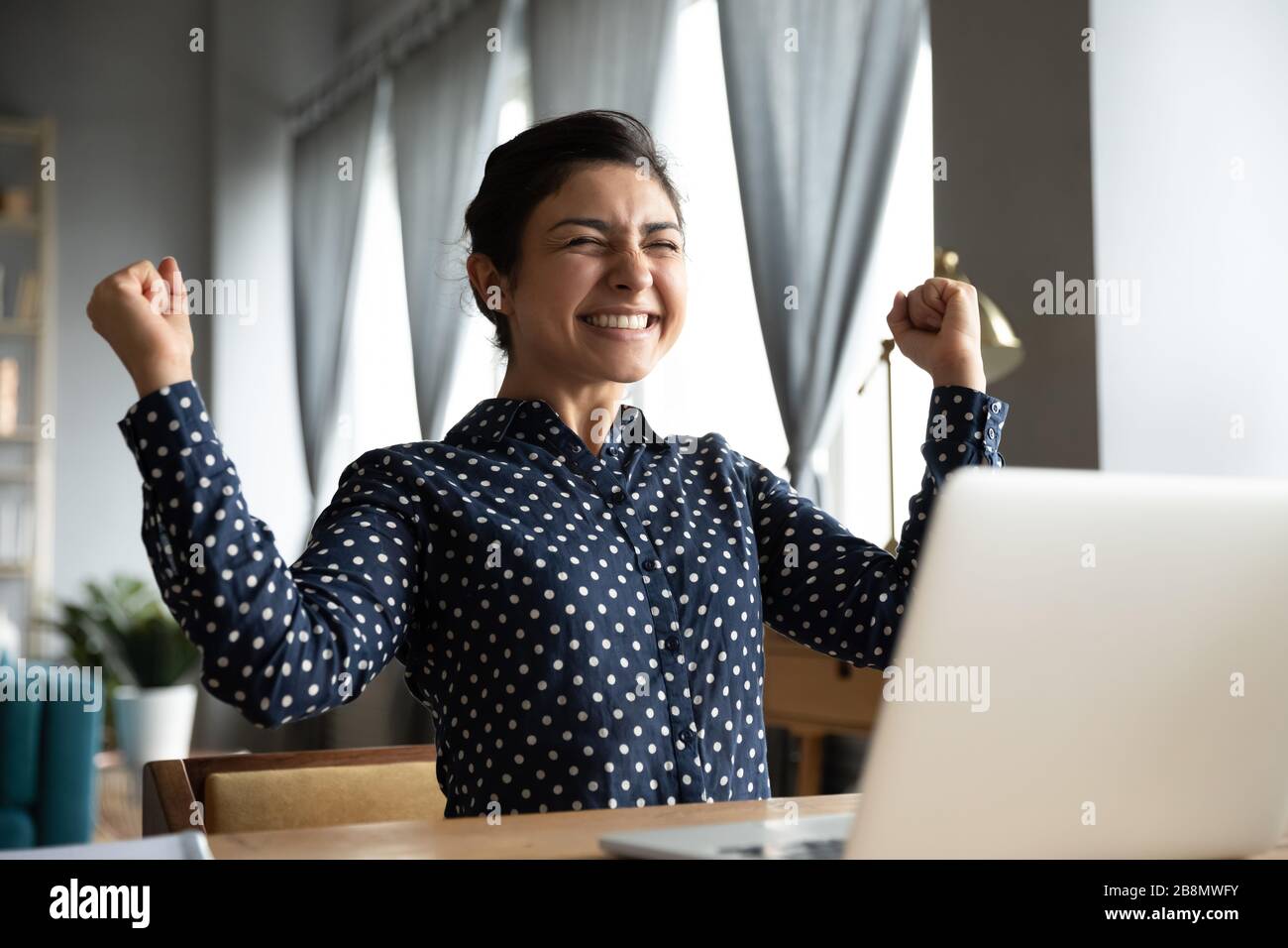 Lächelnde Indianerin begeistert von guten Nachrichten, Erfolg bei der Arbeit Stockfoto