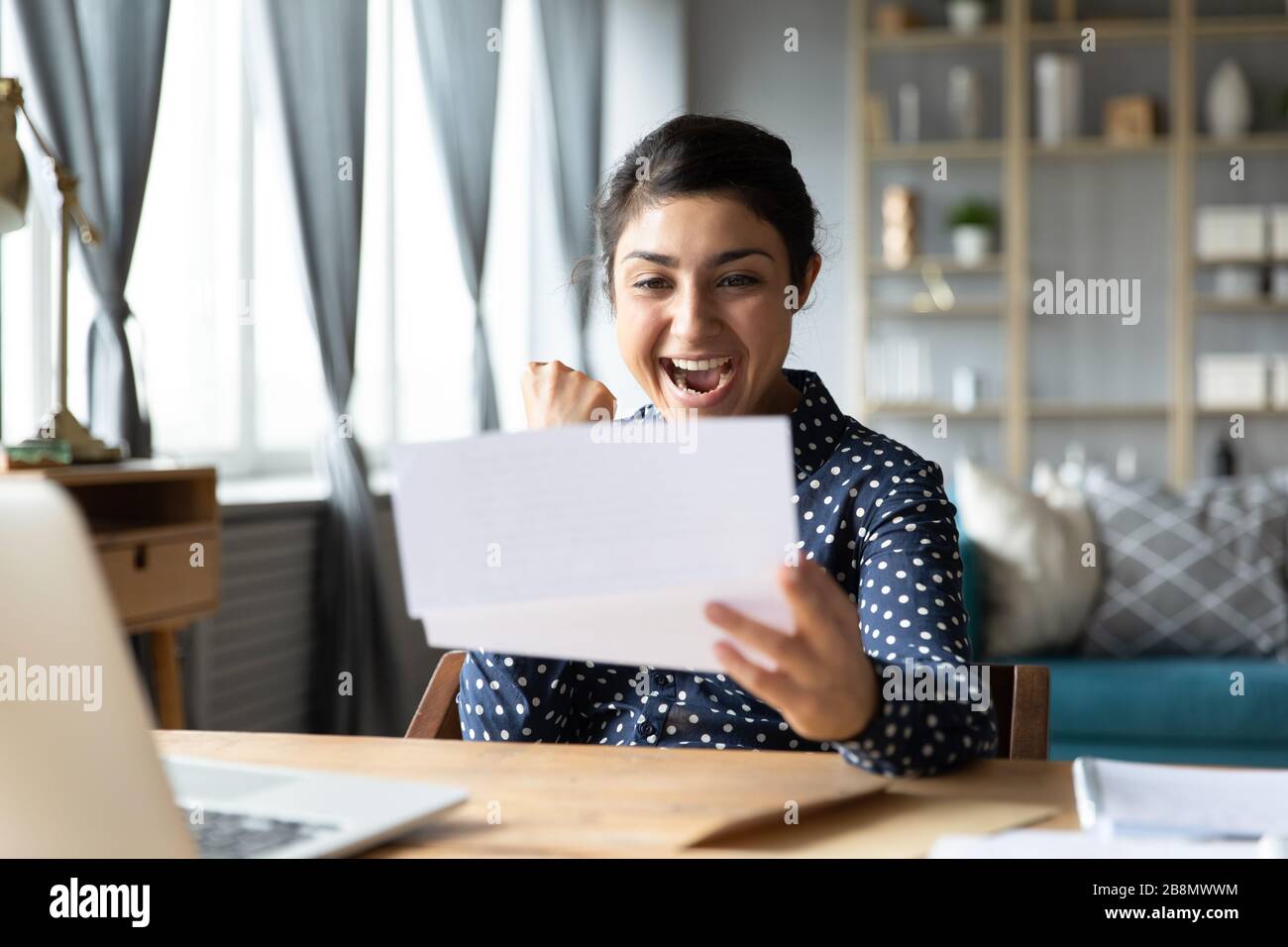Aufgeregtes indisches Mädchen, das gute Nachrichten in einem Brief liest Stockfoto