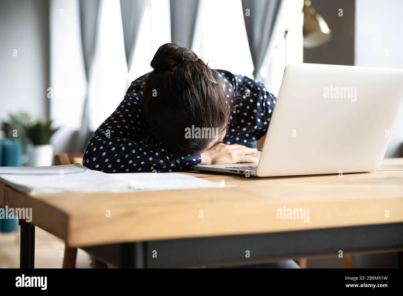 Müde indische Frau schläft und sitzt am Schreibtisch mit Laptop Stockfoto