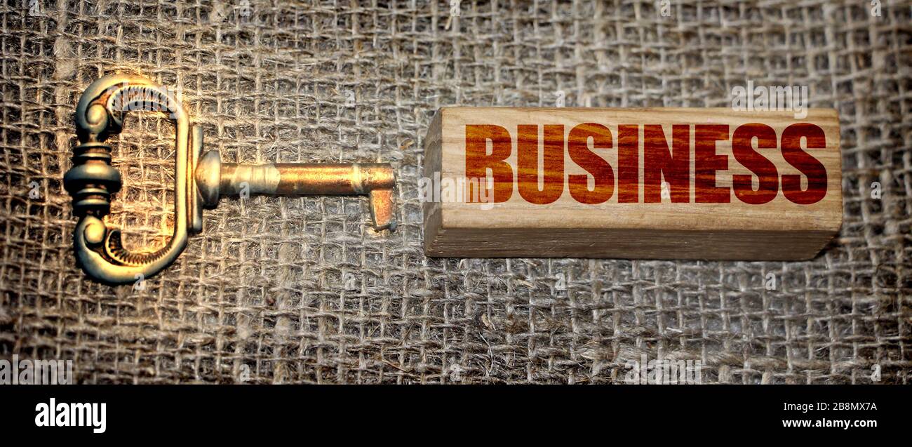 Vintage-Schlüssel und Geschäftswort auf Holzblock auf Leinwand in Burlap Textur. Motivationsschlüssel für Unternehmensneustart für das Unternehmenskonzept Stockfoto