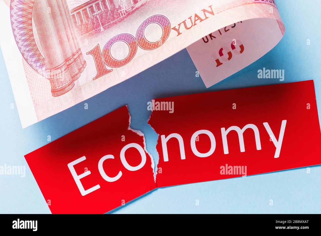 Hundert Yuan und ein zerrissener Tag mit Text. Konzept zum Thema des Wirtschaftsabschwungs im Land und der Währungsabwertung Stockfoto